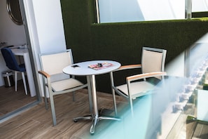 A modern indoor seating area with two chairs and a table, a trash bin, and a window with a view of a building. - IG Nachosol Atlantic & Yaizasol by Servatur (Mogan)