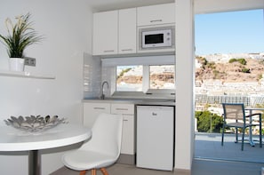 A compact kitchenette with a microwave, a small refrigerator, and a dining area with a chair. - IG Nachosol Atlantic & Yaizasol by Servatur (Mogan)