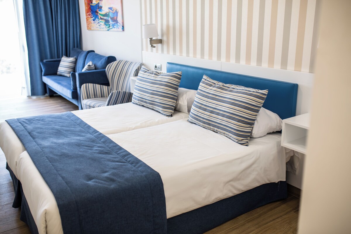 Una habitación de hotel con una cama grande, un sofá y una mesita de noche.