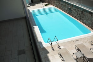 A swimming pool with a stone wall and a tiled deck. - IG Nachosol Atlantic & Yaizasol by Servatur (Mogan)