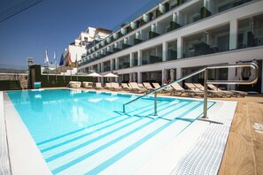 Una piscina con sillas de descanso y barandilla de cristal.