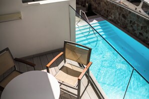A poolside area with a chair and a table, a stone wall, and a clear blue pool. - IG Nachosol Atlantic & Yaizasol by Servatur (Mogan)