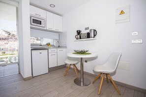 A modern kitchen with white cabinets, a microwave, a coffee maker, and a small dining table with two chairs. - IG Nachosol Atlantic & Yaizasol by Servatur (Mogan)