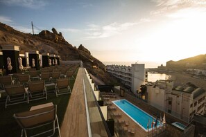 A rooftop terrace with seating and a pool, overlooking a coastal area with buildings and a beach. - IG Nachosol Atlantic & Yaizasol by Servatur (Mogan)