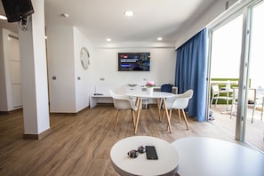 A modern hotel room with a dining area, a TV mounted on the wall, and a balcony with a view. - IG Nachosol Atlantic & Yaizasol by Servatur (Mogan)