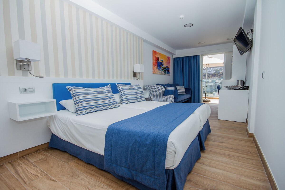 Una habitación de hotel moderna con una cama grande, un escritorio y un televisor.