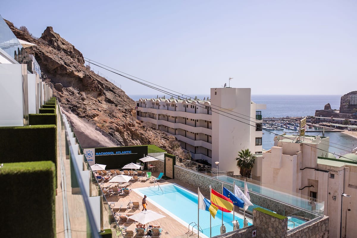Un hotel con piscina, mobiliario exterior y vistas al mar.