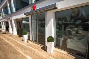 A modern building with glass doors and windows, a reception area, and outdoor seating. - IG Nachosol Atlantic & Yaizasol by Servatur (Mogan)