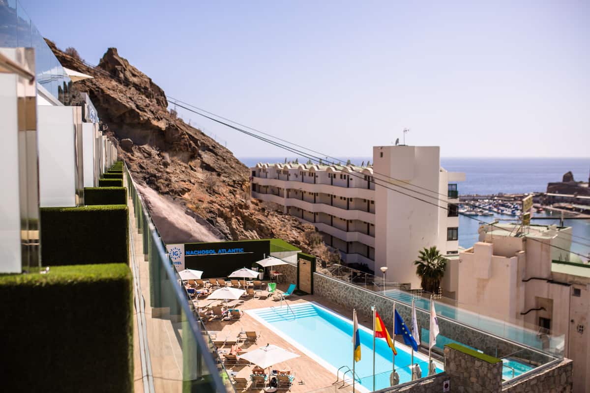 Un hotel con piscina, mobiliario exterior y vista al mar.