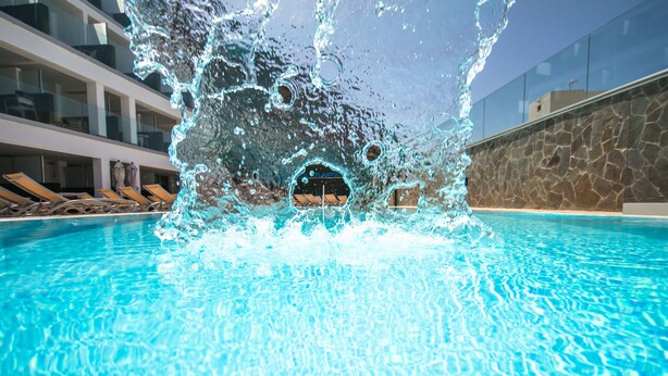 Una piscina con agua cristalina y un chapoteo en el centro.