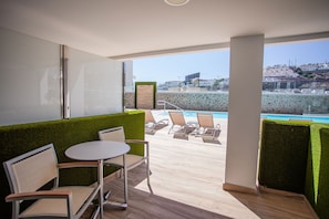 Uma varanda com piscina, espreguiçadeiras e uma mesa.