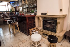 A bar area with a fireplace, seating, and a variety of bottles and glasses.