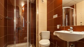 A bathroom with a glass-enclosed shower, a toilet, and a sink with a mirror above it.