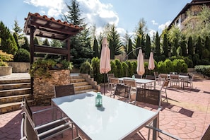 An outdoor patio with stone steps, tables, chairs, and umbrellas. - Orbilux (Bansko)