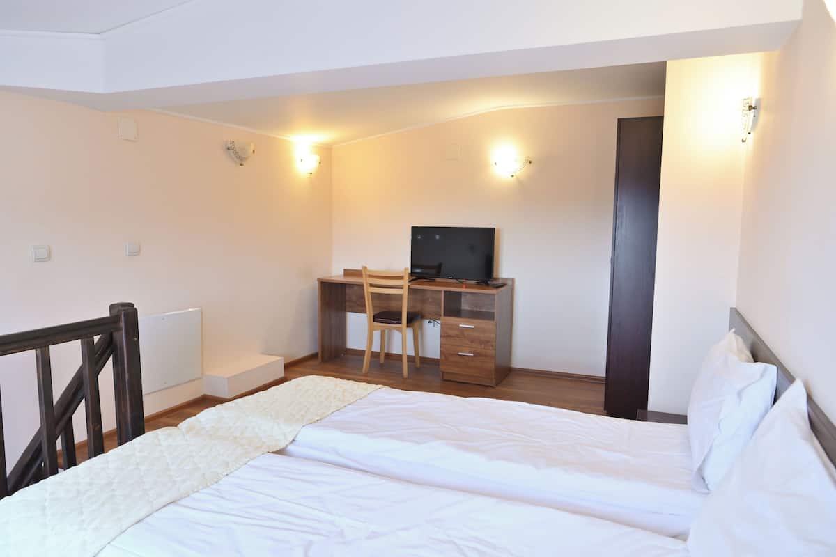 A bedroom with a bed, a desk, and a chair.