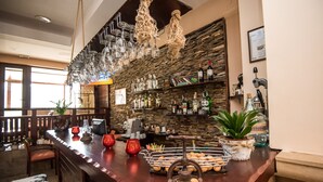 A bar area with a wooden counter, hanging wine glasses, and shelves with bottles. - Orbilux (Bansko)