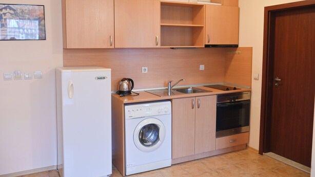 A compact kitchen with a washing machine, a refrigerator, a sink, and a stove. - Orbilux (Bansko)