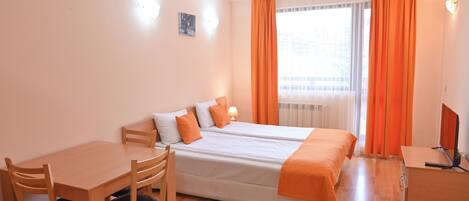 A hotel room with two beds, a desk, and a chair.