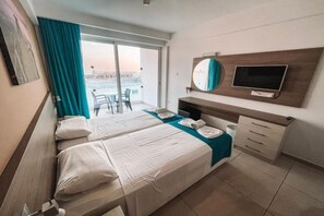 Ett hotellrum med två sängar, en TV, en spegel och en balkong med utsikt.
