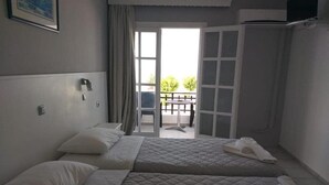 A hotel room with two beds, a balcony, and a view of the outdoors.
