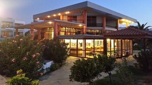 A modern two-story building with a covered outdoor seating area and a glass-enclosed lounge.