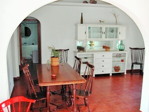 Ein Essbereich mit einem Holztisch und Stühlen, einem weißen Schrank mit Glastüren und einem Fliesenboden.