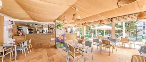 A cafe with outdoor seating, a counter, and a view of the street.