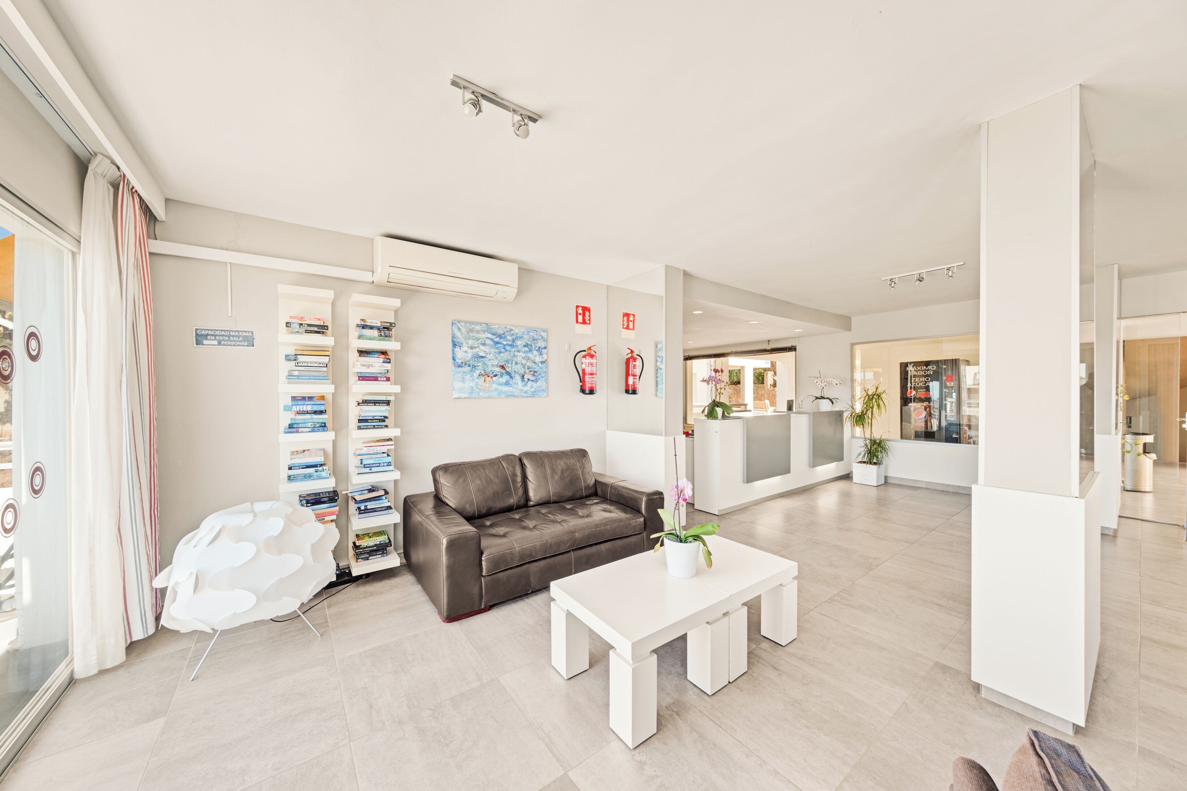 Un salón moderno y luminoso con un sofá de cuero, una mesa de centro blanca y una estantería.