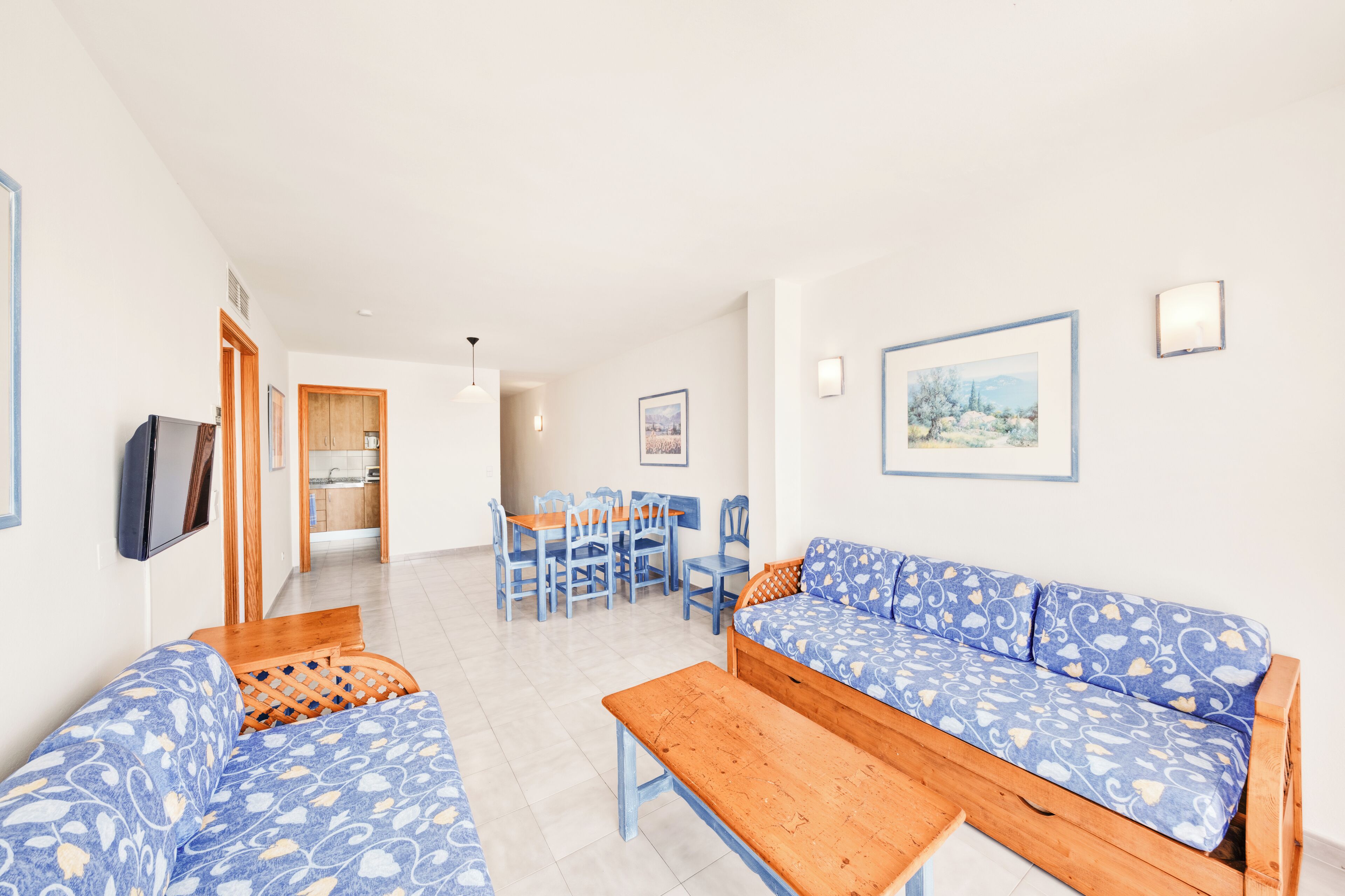 A spacious living area with a sofa set, a wooden bench, and a dining table with chairs.