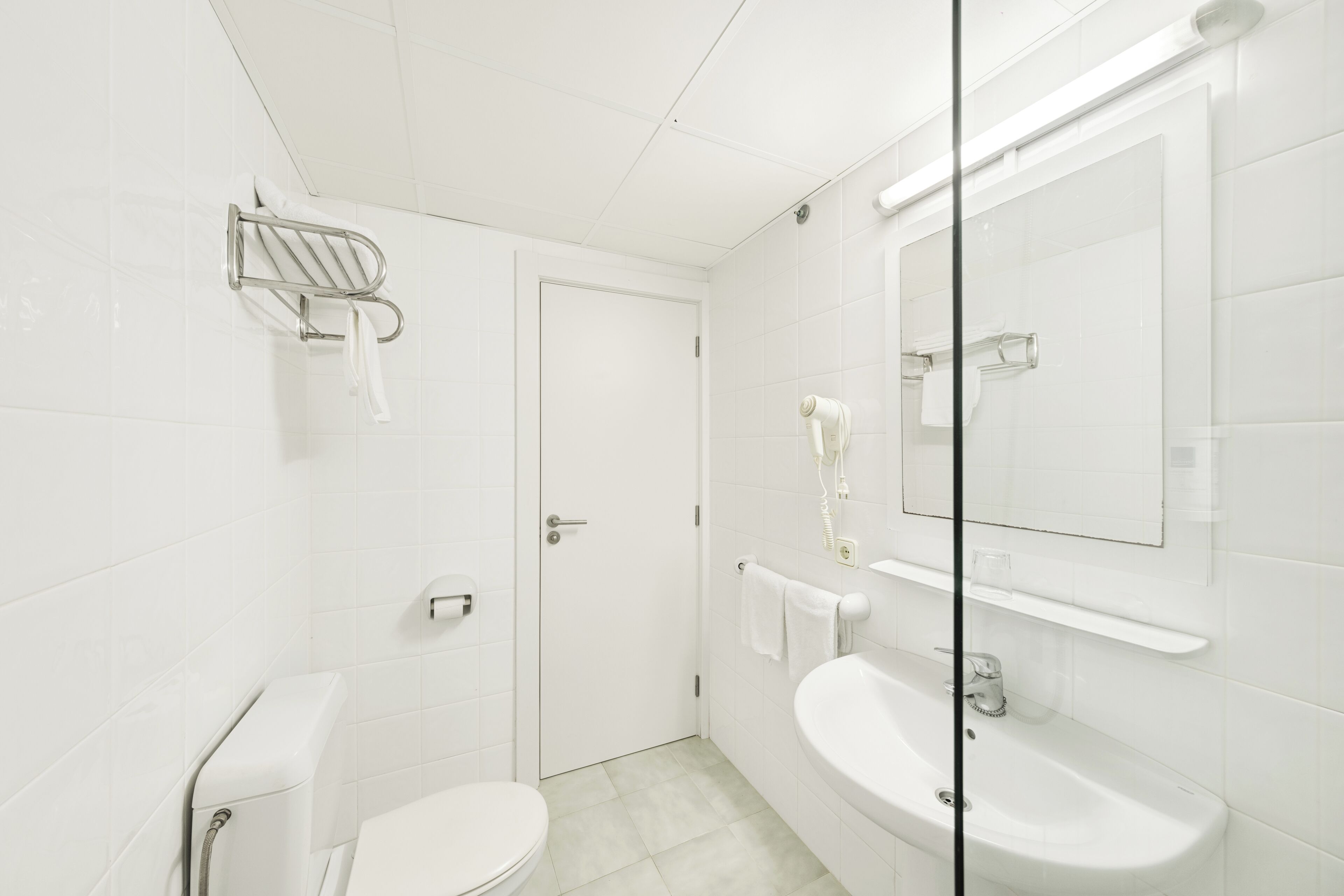 A modern bathroom with a toilet, sink, and glass shower enclosure.