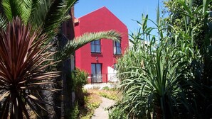 Un edificio rojo con un camino que lleva a la entrada, rodeado de vegetación.