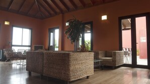 Un vestíbulo amplio con mobiliario de mimbre, una planta grande y un techo de madera.