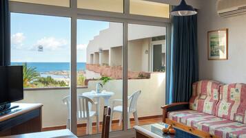 Un balcón con vista al mar, un sofá, una mesa y un televisor.