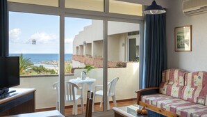 A balcony with a view of the sea, a sofa, a table, and a TV.