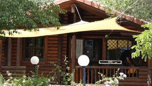 Une cabane en bois dotée d’un porche couvert, d’un haut-parleur et d’une antenne parabolique.