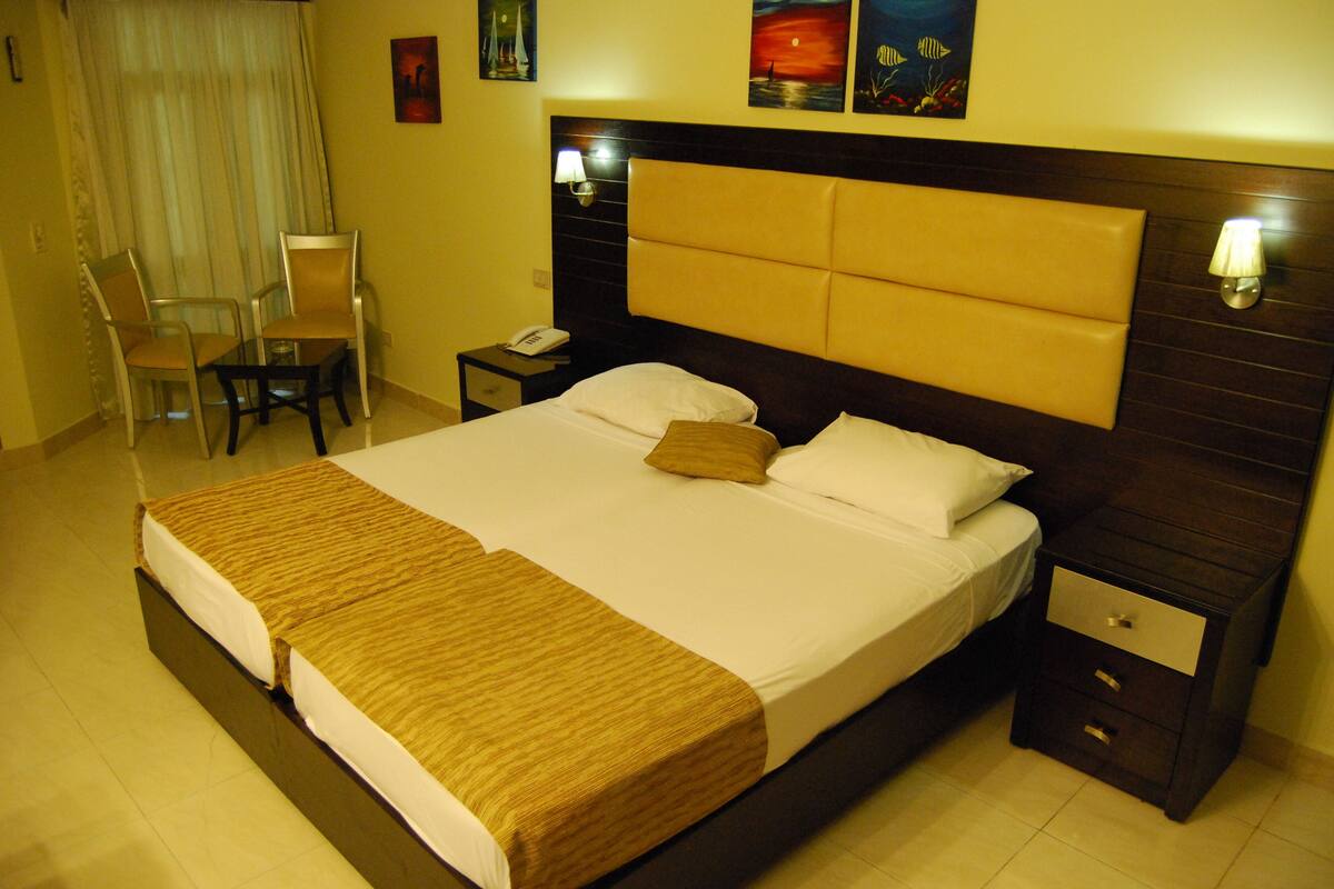 A hotel room with a large bed, a bedside table, a chair, and a nightstand.