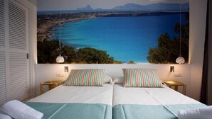 A double bed with striped pillows and a view of a coastal landscape. - Pou Des Pujols (Formentera)