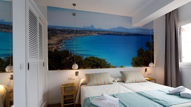 A bedroom with two beds, a large window, and a view of the sea. - Pou Des Pujols (Formentera)