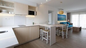A modern kitchen with a central island, white cabinetry, and a microwave. There is a dining area with a table and chairs, and a sofa in the background. - Pou Des Pujols (Formentera)