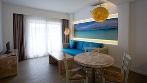 A modern hotel room with a large window, a sofa, a dining table, and a painting of a beach scene. - Pou Des Pujols (Formentera)