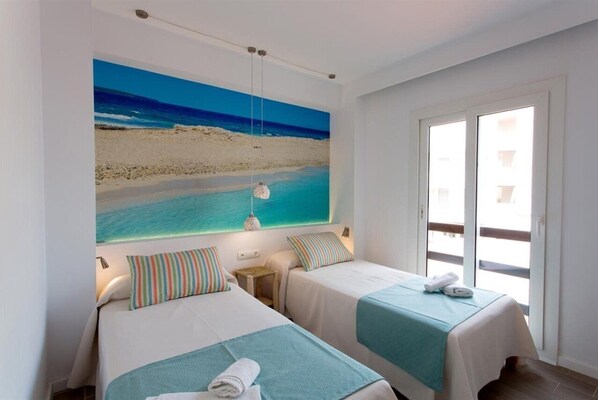 A hotel room with two beds, a large beach mural on the wall, and a sliding glass door to the outside. - Pou Des Pujols (Formentera)