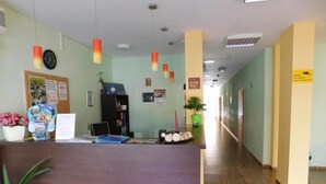 A reception area with a wooden reception desk, a clock, and a bulletin board with notices. - Darius (Sunny Beach)