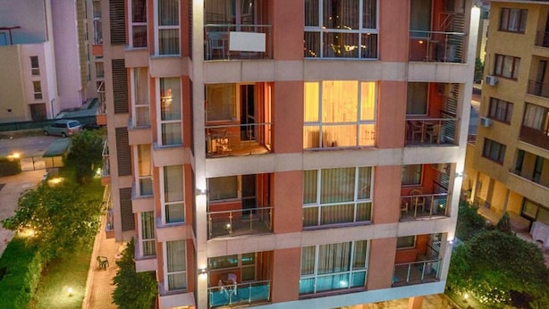 A multi-story hotel with a swimming pool surrounded by lounge chairs and a garden area. - Darius (Sunny Beach)