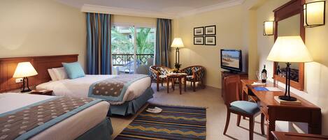 A hotel room with two beds, a desk, a chair, a TV, and a balcony with curtains.