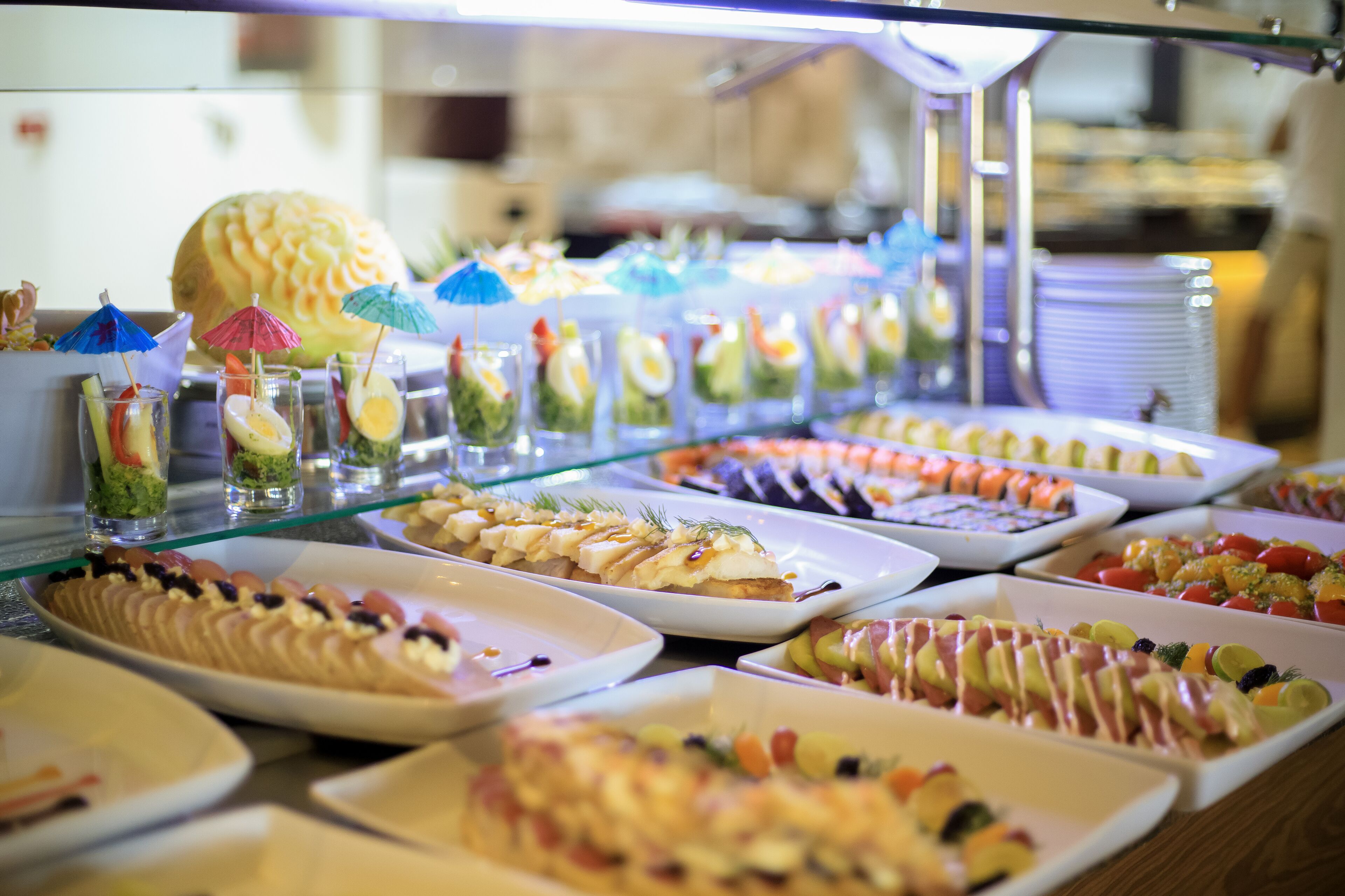 A buffet with various dishes and drinks, including fruit, salads, and desserts.