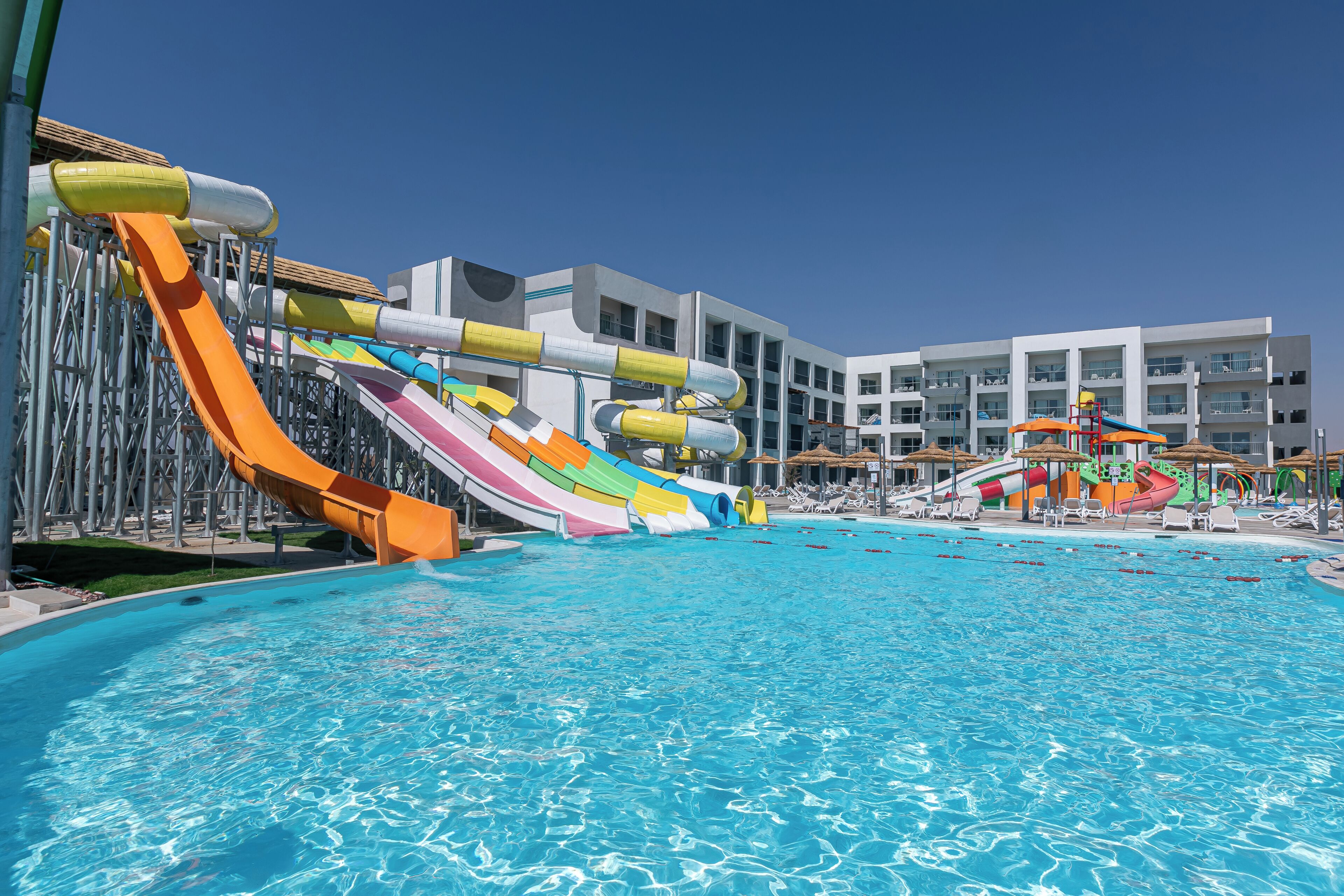 A swimming pool with multiple water slides and lounge chairs.