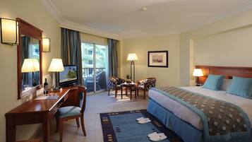 A hotel room with a bed, desk, chairs, and a view of the outdoors.