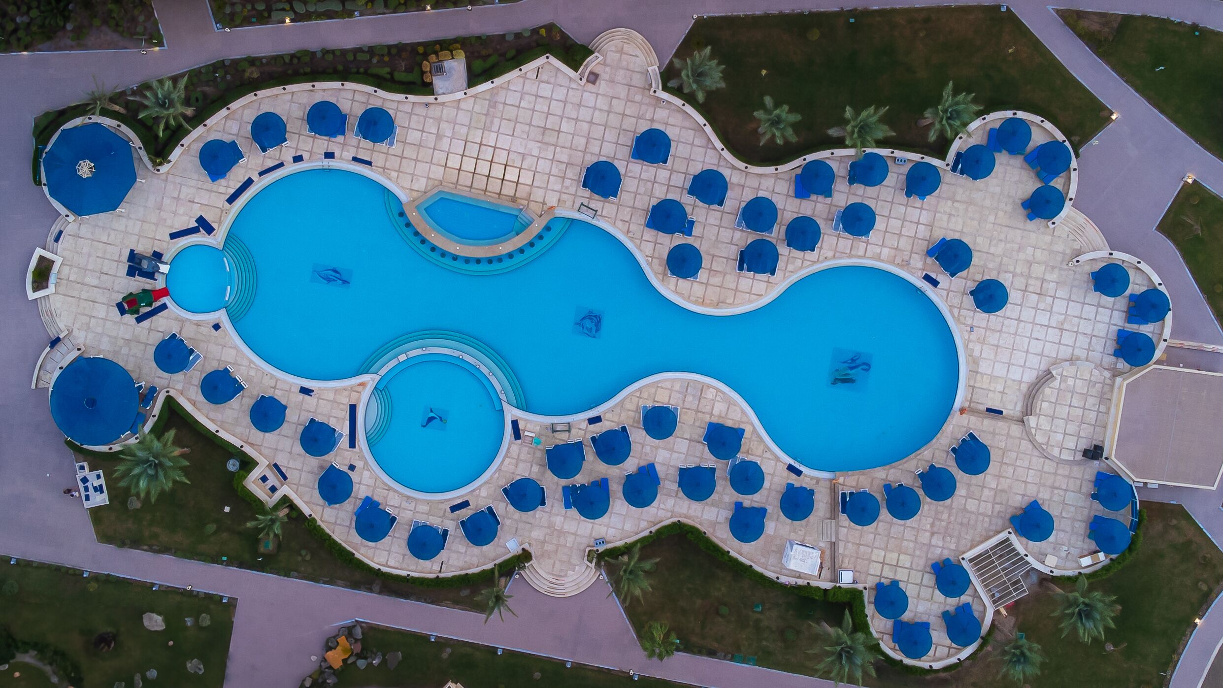 An aerial view of a resort with multiple swimming pools and sun loungers arranged around them.