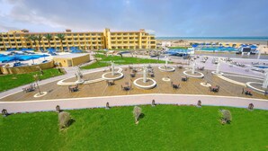 A hotel with a central courtyard featuring circular seating areas, palm trees, and a pool area with umbrellas. - Amwaj Beach Club Abu Soma - All inclusive (Safaga)