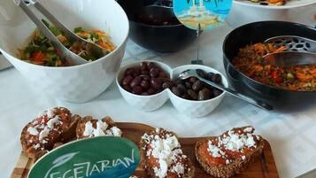 A buffet table with various dishes, including a section labeled "VEGAN" and another labeled "VEGETARIAN".